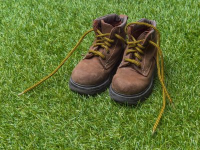 Kids fashion brown boots on green grass background. The concept of the coming winter, selling shoes for children.